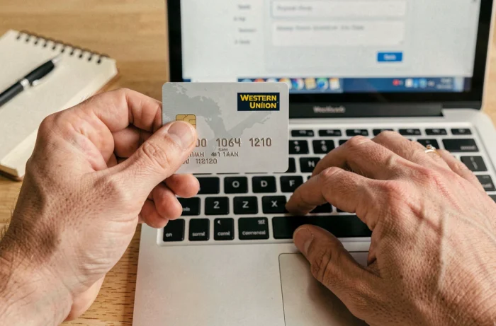 Gros plan de mains tenant une carte bancaire pour réaliser un paiement en ligne sur le site Western Union